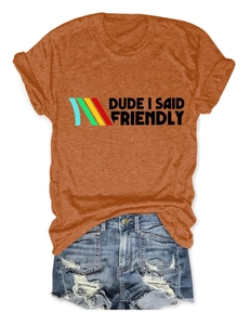 Flat lay of caramel T-shirt with 'Dude I Said Friendly' text and ripped denim shorts