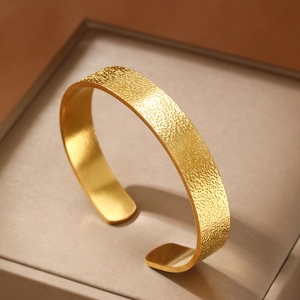 Golden brushed wide open cuff bracelet with hammered rock texture in a luxury jewelry box