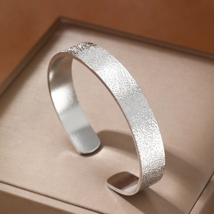 Minimalist wide open cuff bracelet with a matte silver textured finish in a luxury jewelry box