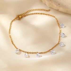 Detail of gold stainless steel anklet with seven teardrop crystals on champagne satin