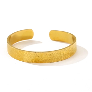 Detail view of the brushed golden texture and C-shape design of the open metal bangle