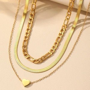 Detail of layered gold necklaces with heart pendant, figaro and snake chain textures