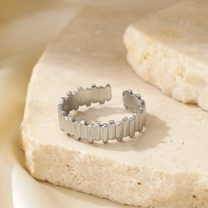 Minimalist geometric open ring in polished stainless steel on a beige stone surface