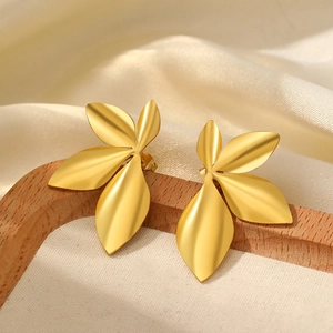 Detail of matte gold leaf studs with a 3D textured design on creamy velvet background