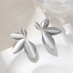Minimalist silver leaf stud earrings with matte metal texture on a white stone base