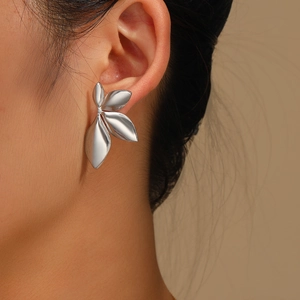 Macro detail of silver leaf earrings in polished stainless steel on female model