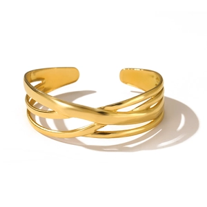 Dettaglio del bracciale rigido dorato a più strati con design incrociato minimalista