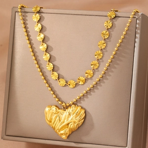 Collana dorata a strati con dischi texture sole e ciondolo cuore su scatola regalo