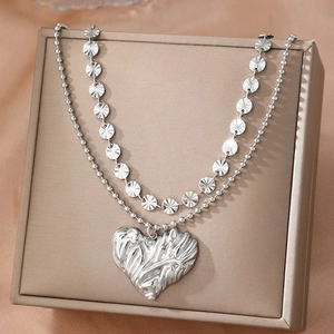 Elegante collana a due strati color argento con ciondolo a cuore su portagioie dorato di lusso