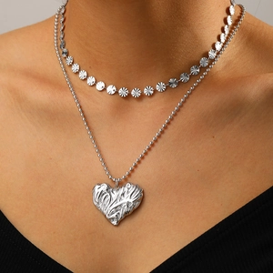 Dettaglio di collana argento a doppio strato con ciondolo a cuore e catena girocollo