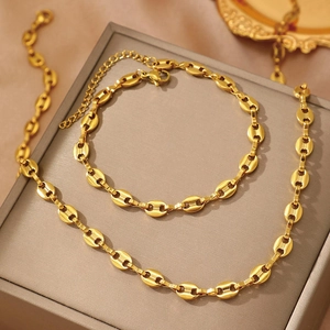 Golden stainless steel coffee bean necklace and bracelet set displayed on a luxury box