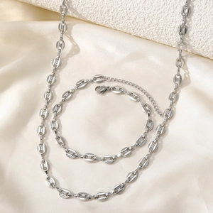 Silver-tone coffee bean link necklace and bracelet set on soft white silk background