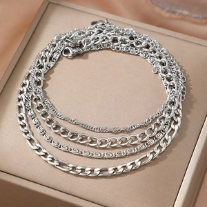 Set of four silver layered chains including Figaro and Curb links on elegant gold silk