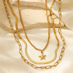 Detail of a 3-layer gold star pendant snake chain necklace on white silk background