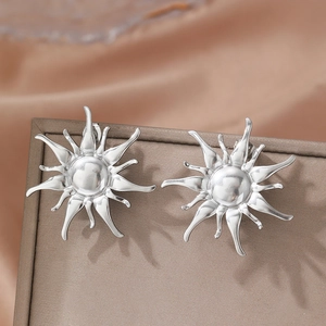 Polished silver sunflower sunburst earrings displayed on a brown leather jewelry box