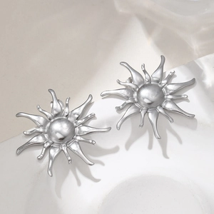 Polished stainless steel sunflower starburst stud earrings on a textured stone surface