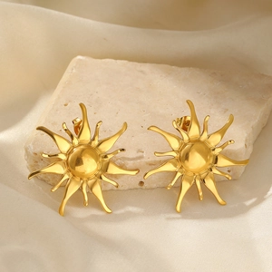 Detail of sunbeam gold earrings on stone base showing matte finish and artistic ray design