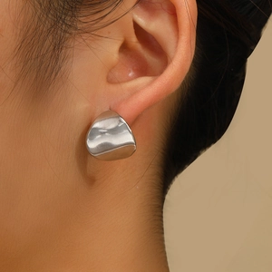 Macro shot of silver liquid-metal stud earring on ear with polished finish