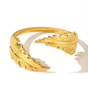 Golden feather shaped open ring in stainless steel with detailed textures on white background