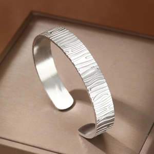 Minimalist silver cuff bracelet featuring unique wood grain texture and polished inner band
