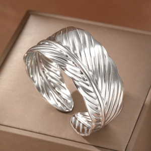 Polished stainless steel feather cuff bracelet with detailed texture on a display box