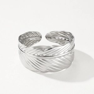 Macro shot of silver feather bangle showing intricate metal carving and adjustable opening
