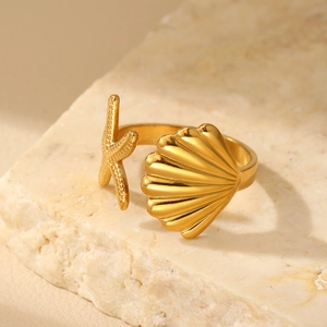 Detailed close-up of golden sea star and shell ring on a textured stone display