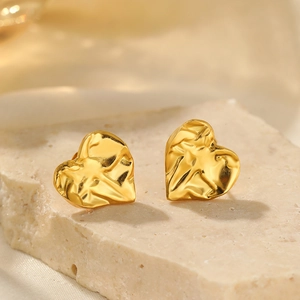 Macro shot of gold heart stud earrings with vintage pleated wave texture on stone