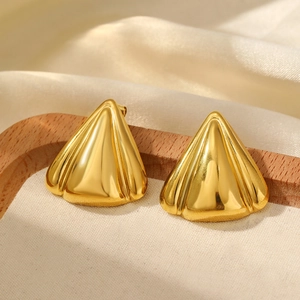 Macro shot of 18K gold plated triangular earrings with elegant ribbed texture on fabric