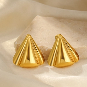 Detail of 18K gold plated triangular earrings placed on elegant beige silk and stone