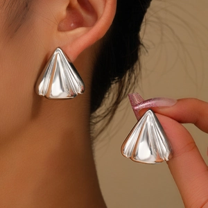 Macro view of silver triangular earrings with vertical striped texture and metal finish