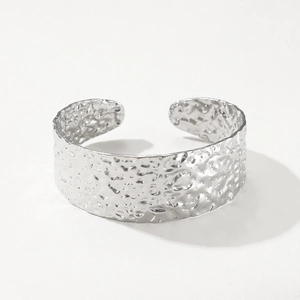 Detail van de zilveren open armband met een unieke gehamerde metaalstructuur