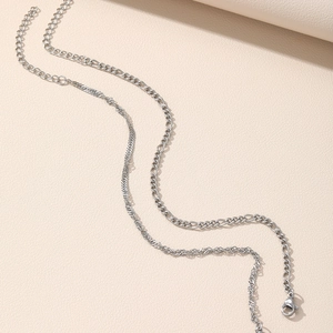 Detail of silver Figaro and twisted rope chains with lobster clasp on beige texture