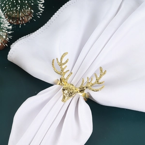 Golden reindeer metal napkin ring with white fabric napkin on a festive table setting