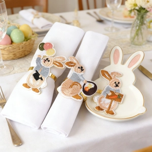Detail of embroidered rabbit napkin ring with golden metal loop and bunny plate
