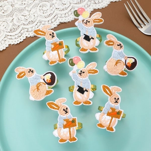 Detail view of seven colorful embroidered bunny napkin rings with gold metal bands