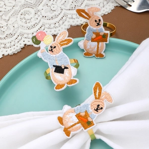 Detail of embroidered rabbit napkin ring with balloons and carrots on gold metal base