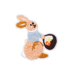 Detail of embroidered bunny napkin ring with blue coat and flower basket for table decor