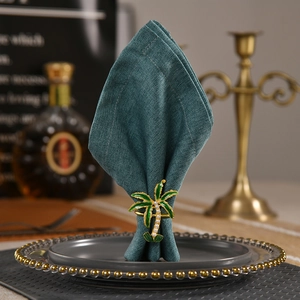 Tropical coconut tree napkin ring with green enamel and pearls on dark fabric
