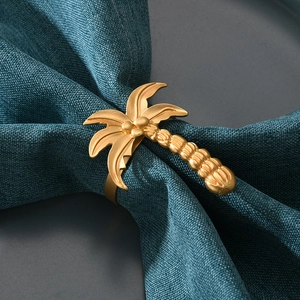 Macro shot of tropical gold coconut tree napkin ring with pearl on green linen fabric