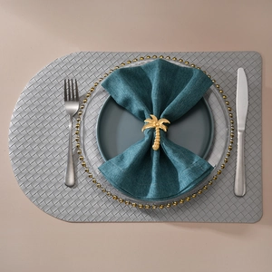 Detailed close-up of a golden palm tree napkin ring on a dark green folded cloth napkin