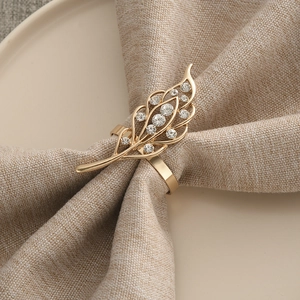 Golden feather napkin ring with rhinestones on linen napkin and cream ceramic plate