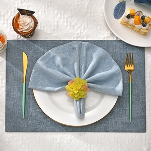 Close-up of artificial succulent plant napkin ring on a blue fabric napkin with gold cutlery
