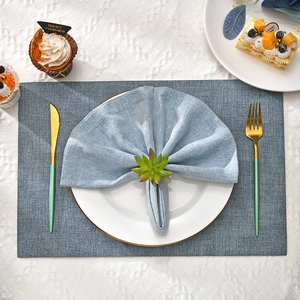 Detailed top view of a green succulent napkin ring on a blue linen napkin with gold cutlery
