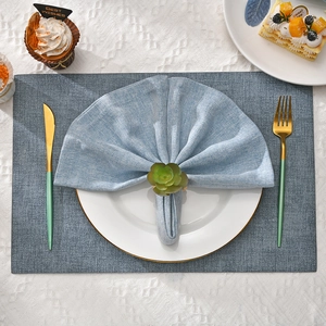 Close-up of succulent napkin ring on blue linen napkin with elegant gold cutlery set