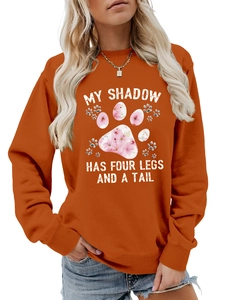 Dettaglio della felpa rosso ruggine con testo My Shadow Has Four Legs e zampa floreale