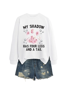 Dettaglio felpa bianca con stampa My Shadow Has Four Legs e pantaloncini di denim