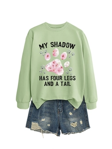 Dettaglio della felpa verde chiaro con stampa artistica e pantaloncini di jeans blu