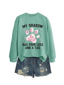 Dettaglio felpa verde menta con stampa My Shadow e pantaloncini di denim strappati