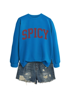 Close-up of SPICY letter print on royal blue crewneck sweatshirt with distressed denim shorts